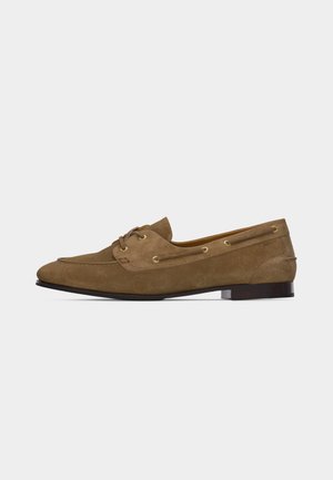 Mocassin pour homme en daim marron avec détails en lacets, talon bas et bout rond, présenté de profil sur fond blanc.