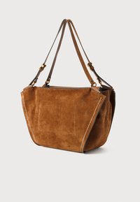 Brun mocka toteväska med dubbla läderhandtag, med en framficka och vit sömnad längs sidorna. Öppen toppdesign.