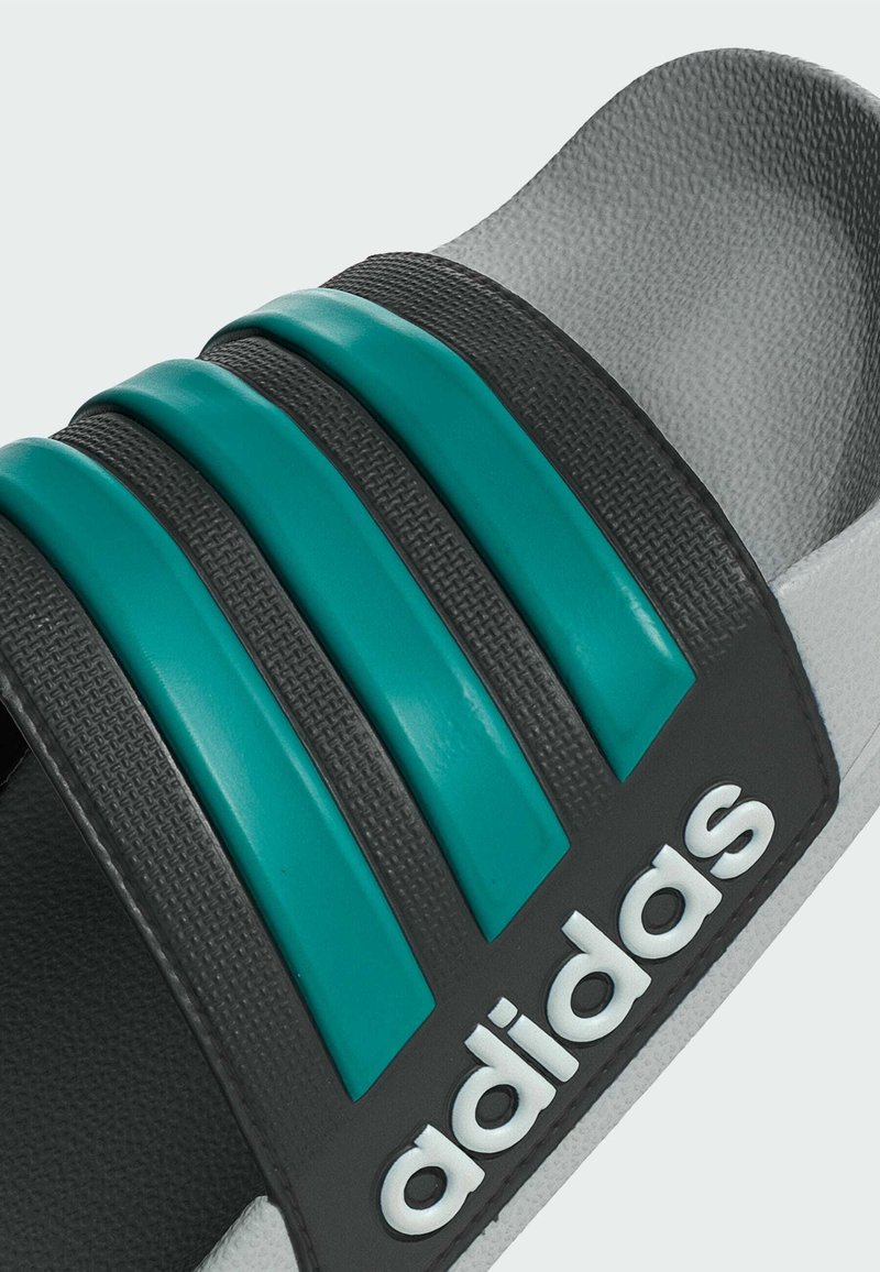 Sort slidesandal med tre tealfarvede striber, struktureret overdel og hvidt logo. Polstret sål med buet design for komfort.
