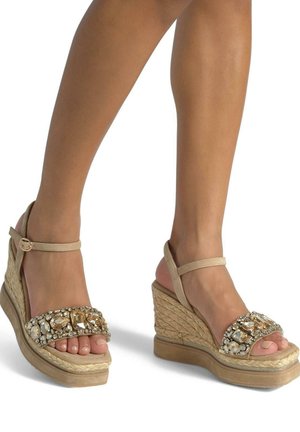Sandali con zeppa beige dal design espadrilles, caratterizzati da un cinturino con gioielli per abbellimento e una base intrecciata testurizzata.