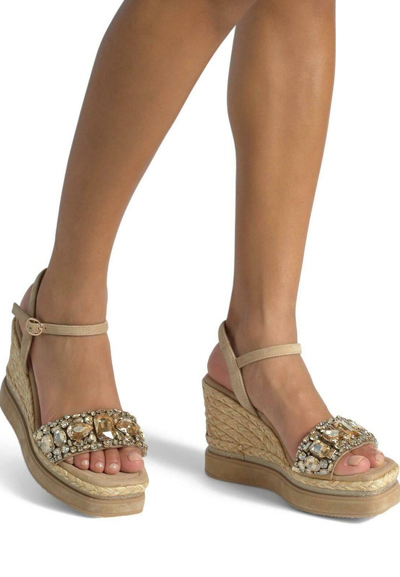 Sandalias de cuña beige con un diseño de espadrille, que cuentan con una correa adornada con joyas y una base texturizada de tejido.