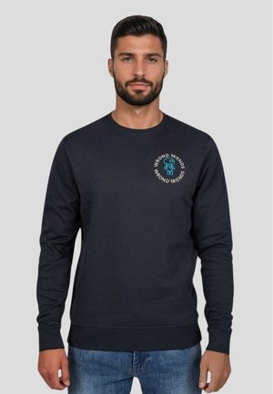 Sudadera azul marino hecha de una mezcla de algodón, con un cuello redondo y puños acanalados. Un logo impreso con un adorno de dibujos animados se encuentra en el pecho.