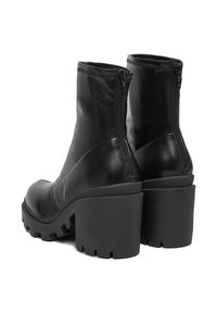 Melnas ādas potītes zābaki ar masīvu augstu papēdi, sānu rāvējslēdzējiem un teksturētām zolēm ar dziļām rievojumiem, kas nodrošina saķeri un stabilitāti.