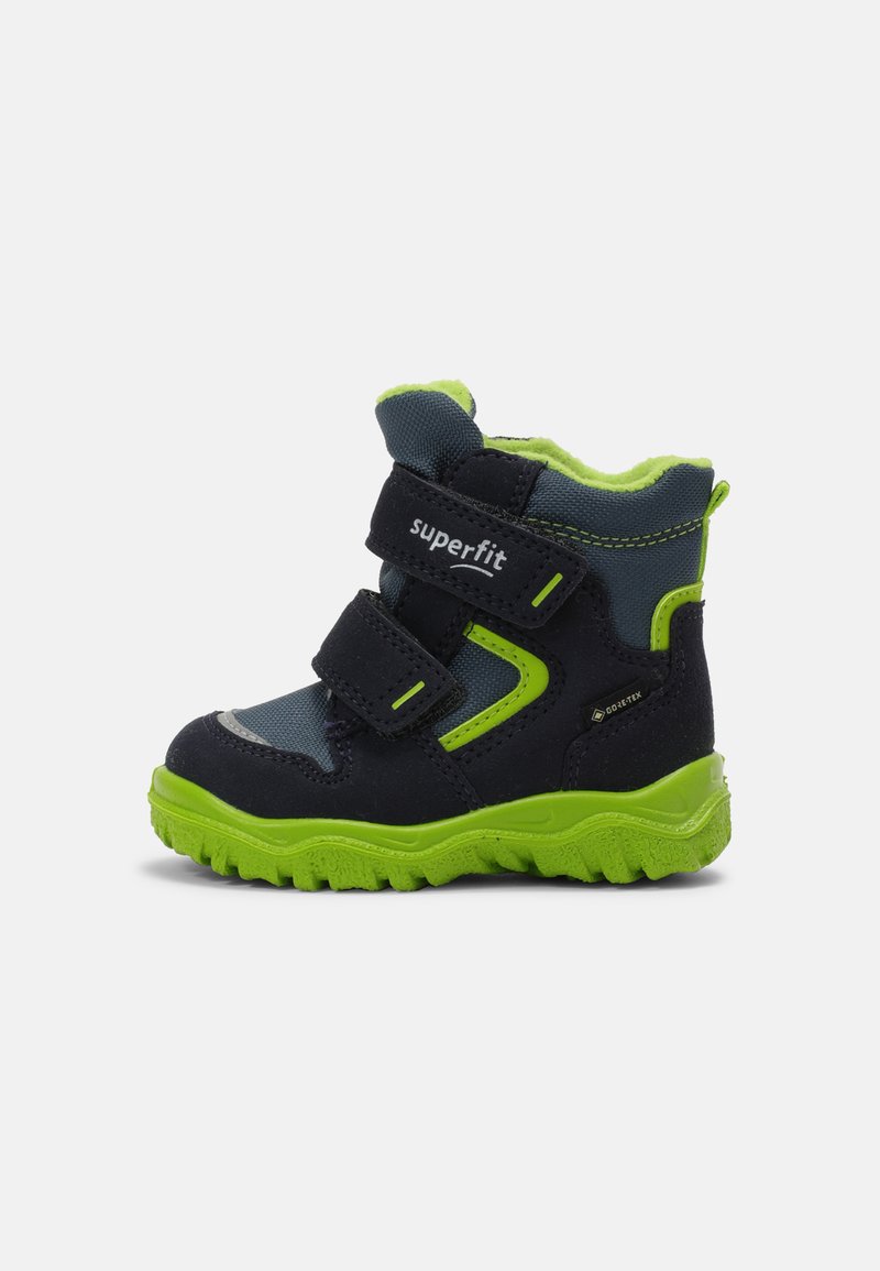 Botas infantiles en azul oscuro y gris con acentos verdes, dos correas de Velcro, suela resistente y un forro suave. Diseño ligero y duradero.