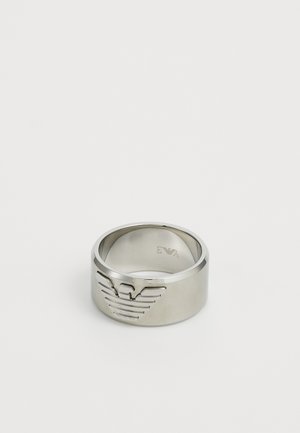 Sølvmetalring med et hævet ørnelogo-design på den ene side, glat bånd og poleret overflade. Graveret branding indeni.