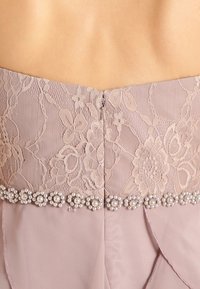 Jasně fialové šaty s krajkovým trupem s květinovým vzorem, zadním zipem a ozdobou z perel v pase. Hladká textura.