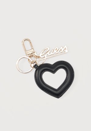 Llavero en forma de corazón de cuero negro con charm del logotipo Guess en metal dorado y clip redondo para llaves sobre fondo liso.