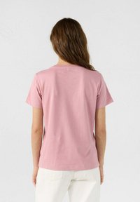 Camiseta de manga corta y cuello redondo en suave algodón rosa con un corte relajado, textura suave y sutiles detalles de costura en el dobladillo.