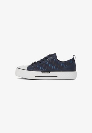 Sapatilha navy com padrão geométrico em azul e preto, biqueira de borracha branca, sola texturizada branca e detalhes de marca na lateral.