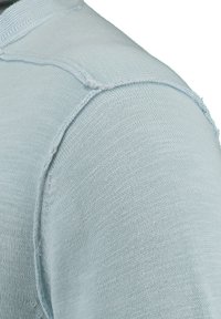 Maglione a maglia di colore azzurro chiaro con collo tondo, dotato di cuciture a vista e tessuto testurizzato nella zona delle spalle. Design morbido e aderente.