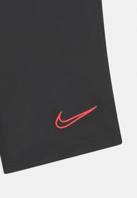 Svart tyg med en röd Nike swoosh-logotyp broderad nära nederkanten.