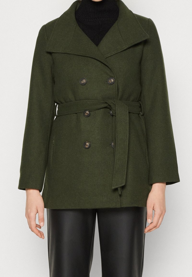 Abrigo de mezcla de lana en verde oliva, con un amplio cuello, botones de doble botonadura, cintura ceñida con cinturón y mangas largas. Tela texturizada y dos bolsillos.