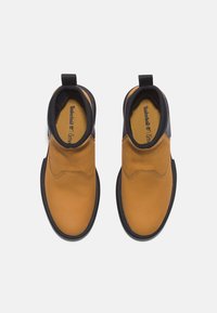Braune Lederstiefeletten mit schwarzem oberen Teil. Gummisohle, runde Zehenpartie und elastische Seitenpaneele für einfaches An- und Ausziehen. Timberland-Logo innen.