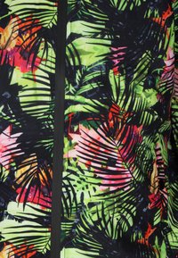 Ropa colorida que presenta un vibrante estampado de hojas tropicales en verde, rosa y negro, con un zipper central negro y una textura suave.