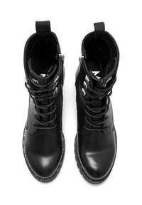 Botas de tobillo de cuero negro con un acabado liso, diseño con cordones, cremallera lateral y tachuelas decorativas a lo largo de la suela. Punta redondeada.