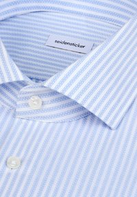 Chemise à rayures bleu clair et blanc avec des boutons, en tissu doux, col standard, et une étiquette portant la mention "seidensticker". Deux boutons visibles.