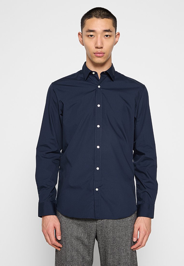 Camicia a maniche lunghe blu navy in tessuto morbido, con colletto button-down, bottoni frontali e vestibilità su misura.