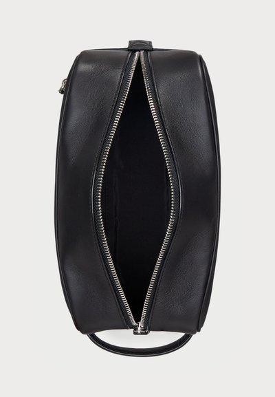 Sac en cuir noir de forme rectangulaire, avec une fermeture éclair argentée qui court le long du haut, révélant un intérieur à doublure sombre.