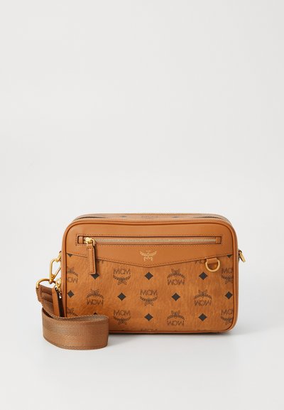 Beige Handtasche mit MCM-Logo-Muster, ausgestattet mit einem Reißverschluss, einer Vordertasche und einem verstellbaren Tragegurt. Hergestellt aus strukturiertem Leder.