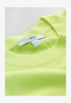 Neona zaļš džemperis no mīksta auduma ar ribotu apkakli un iešūtu birku ar uzrakstu "NEXT" melnā krāsā.