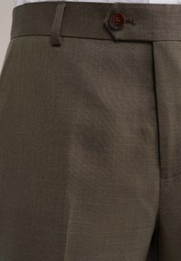 Barna, átlagos vágású nadrág texturált anyagból, elöl gombos záródással és szépen vasalt redőkkel a kifinomult megjelenésért.