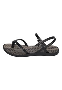 Black sandals with multiple overlapping straps, a textured grey insole featuring a herringbone pattern, and a low flat sole.