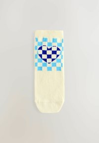 Krämfärgad strumpa med ett blått och ljusblått rutmönster och en hjärtdesign i mitten. Enkelt och lekfullt mönster.