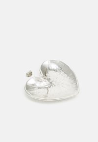 Plato de metal en forma de corazón con un acabado plateado brillante. Presenta un interior texturizado con líneas radiales y un pequeño detalle de pin central.
