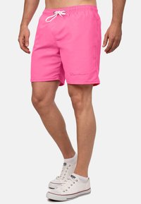 Shorts de bain roses en tissu léger, dotés d'une taille élastique avec cordon de serrage et d'un petit logo sur le côté.