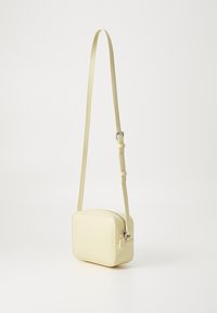 Żółta skórzana torebka crossbody w kształcie prostokąta, z regulowanym paskiem i srebrnym zamkiem błyskawicznym. Gładka tekstura, minimalistyczny design.