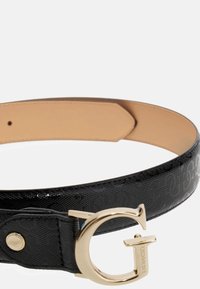 Svart lærbelte med preget logo-mønster, gullfarget G-formet spenne, glatt overflate og tan (brun) underside.