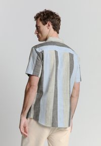 Korte mouwen shirt met verticale strepen in lichtblauw, grijs en wit. Heeft een button-down kraag en een losse pasvorm.