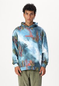 Multicolored hoodie featuring a blue base with vibrant abstract patterns, an adjustable hood, and elastic cuffs and hem. Red logo detail visible.