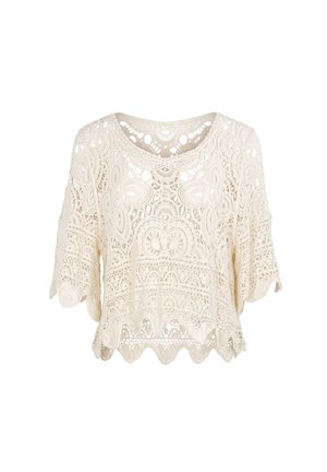 Blouse en dentelle crochet crème à manches courtes et ourlet festonné avec des motifs floraux et géométriques.