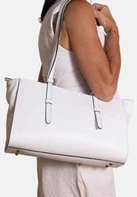 Borsa tote in pelle bianca con superficie testurizzata, caratterizzata da cuciture nere a contrasto, due manici e dettagli in metallo dorato.