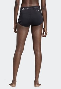 Černé sportovní šortky s vysokým pasem, na kterém jsou loga "Adidas" a "Stella McCartney". Hladká, elastická látka, délka do poloviny stehenní části.