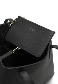 Zwarte gegrainde leren totebag met een kleinere bijpassende pouch. Gouden hardware accenten, waaronder een rits en sluiting.