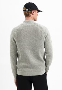 Lichtgrijze gebreide trui met ribbelpatroon bij de hals en mouwen, met een klassieke pasvorm en comfortabele textuur.