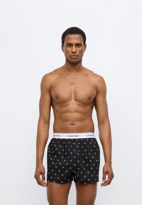 Μαύρα μποξεράκια Calvin Klein με λευκή μέση που έχει λογότυπο, με επαναλαμβανόμενο μικρό μοτίβο λογότυπου. Λείο ύφασμα με άνετη εφαρμογή.