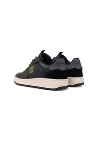 Zwarte sneakers met een bovenwerk van gestructureerd leer en suède, een crèmekleurige tussenzool, een dikke rubberen buitenzool en een opvallend logo aan de zijkant.