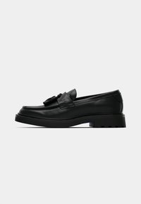 Black leather loafers with a rounded toe, tassel detail, and thick rubber sole. Features stitched accents along the upper and a smooth texture.
