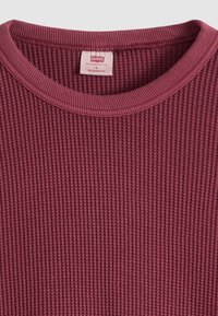 Μπέρντινγκ πουλόβερ με πλέξη βάφλ και στρόγγυλη λαιμόκοψη, με ριμπ ύφανση στη λαιμόκοψη και ετικέτα Levi's που δείχνει μέγεθος M και άνετη εφαρμογή.