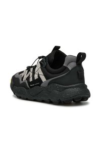 Scarpa atletica nera con suola in gomma testurizzata, dettagli grigi e lacci elastici. Presenta un design robusto con dettagli riflettenti.