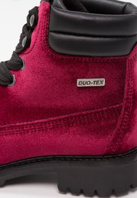 Botte de randonnée en velours bordeaux avec col rembourré noir, lacets noirs, étiquette métallique "DUO-TEX" et semelle noire robuste.