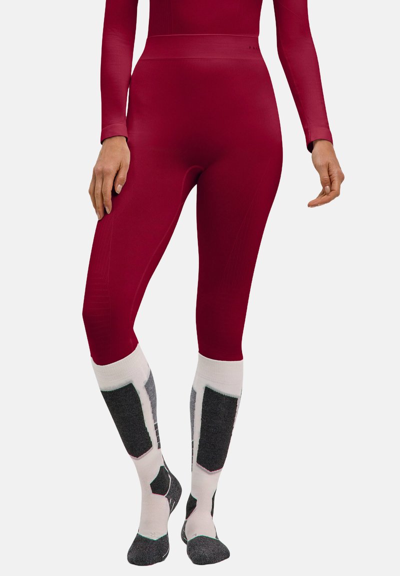 Rode high-waisted leggings, gemaakt van rekbare stof, met een geribbelde textuur. Gecombineerd met kniekousen met grijs-witte patronen.