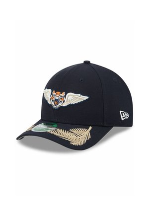 Navy blue baseball cap featuring an embroidered tiger with wings, decorative tan floral embroidery, and a green logo sticker on the brim.
