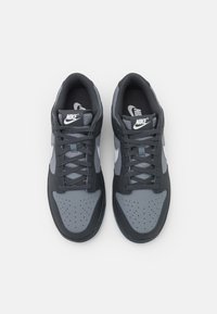 Nike sneakers featuring a mix of dark grey and light grey materials, rounded toe, laces, and perforations on the toe for ventilation.