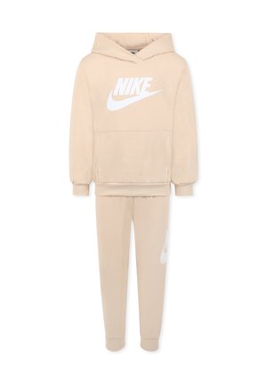 Hoodie beige Nike avec un grand logo blanc sur le devant, associé à un jogger beige assorti avec un petit logo blanc sur le côté. Matériau en coton.