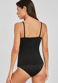 Black tank top with thin straps, smooth texture, fitted design, and a rounded hem. Pairing with low-rise black briefs.