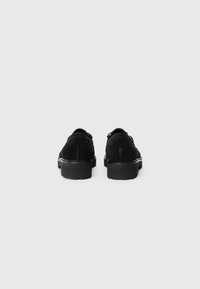 Schwarze Wildlederschuhe mit klobiger Sohle, die mit doppelten Schnallenakzenten und einem glatten Oberdesign versehen sind. Klassische Silhouette mit strukturiertem Finish.